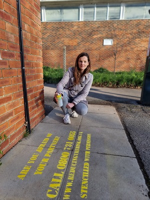 A picture of Cllr Maggie Filipova-Rivers stencilling in Goring to raise awareness of support for victims of domestic abuse