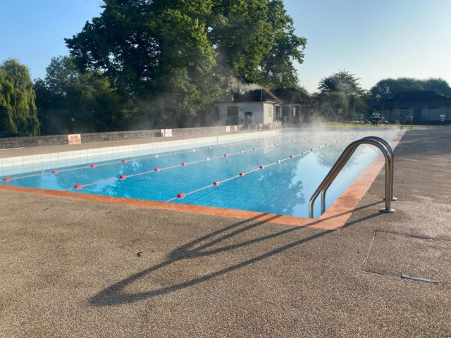 Picture of the outdoor pool in Wallingford. It's a sunny day and there is steam coming off the pool