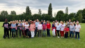Celebrating the Platinum Jubilee with Nordic Walkers in Sutton Courtenay - a group of nordic walkers on a playing field smiling and facing the camera. Some have jubilee bunting in their hands