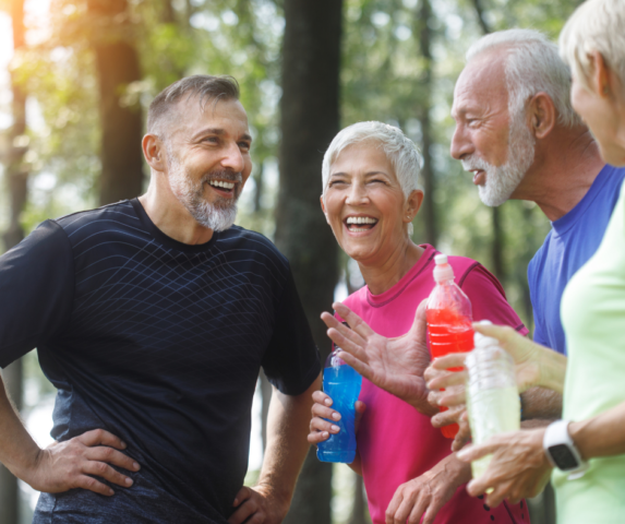 An image of a group of older people chatting outdoors, they look happy and are wearing active clothing